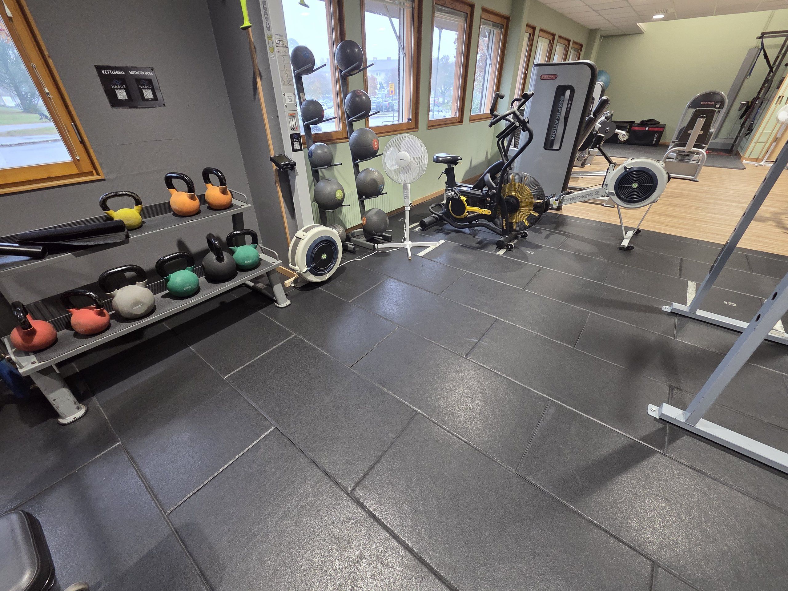 Kettlebells, viktbollar, airbike, roddmaskin och stakmaskin vid fönstren